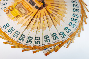 Circular arrangement of 50 euro banknotes fanned out in a complete ring on a white background, symbolizing wealth, finance, and economic prosperity.