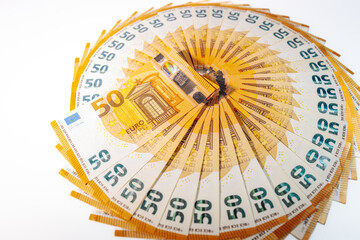 Circular arrangement of 50 euro banknotes fanned out in a complete ring on a white background, symbolizing wealth, finance, and economic prosperity.