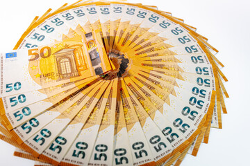 Circular arrangement of 50 euro banknotes fanned out in a complete ring on a white background, symbolizing wealth, finance, and economic prosperity.