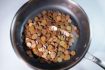 A frying pan filled with euro cent coins, symbolizing money, savings, financial struggles, or the concept of cooking up wealth and economic value.