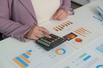 Financial Analysis. Professional accountant using calculator and reviewing charts for budget planning.