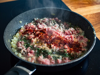 Frying bolognese sauce - minced pork meat with onion in frying pan