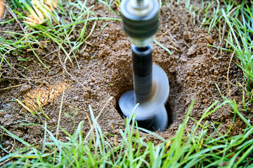 Garden auger drill bit digging hole in soil for planting and construction work
