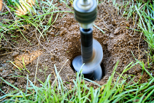 Garden auger drill bit digging hole in soil for planting and construction work - Powered by Adobe