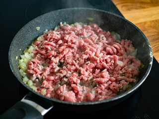 Frying bolognese sauce - minced pork meat with onion in frying pan