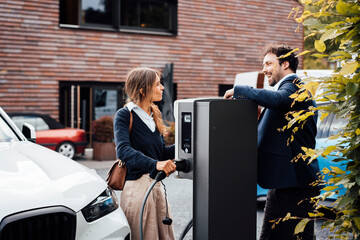 Business partners discussing next to electric vehicle charging station