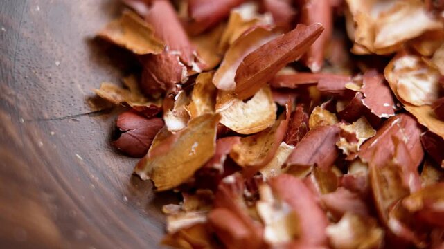 Brown peanut skins or groundnut husk in textured wooden dish. Macro. Rotation