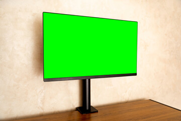 Computer monitor with green screen on wooden desk in modern interior, perfect for mockup design, creative projects and digital workspace visualization.