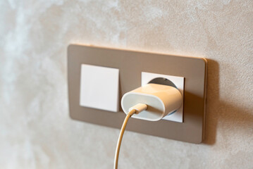 Close-up of electrical socket with plug and USB cable in modern interior, symbolizing electricity, technology and digital connection at home.