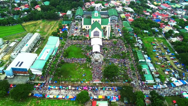 Drone shot of a large Catholic church with thousands of people during a religious event.