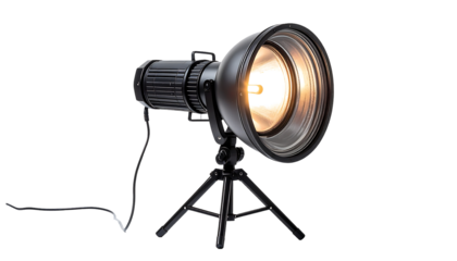 A black, metallic spotlight on a small tripod, illuminated with a warm-toned bulb, emits a bright beam; a power cord is visible