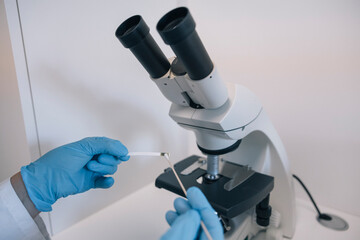 Doctor wearing blue gloves preparing a sample for microscopic examination in a medical laboratory