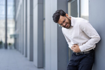 Man holding his stomach in discomfort and pain from indigestion, food poisoning, or cramps, feeling...
