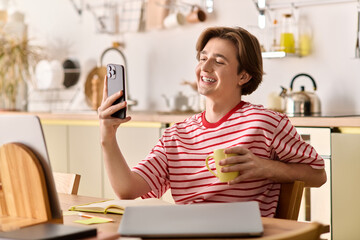 Young man enjoys online study session in modern apartment while sipping coffee