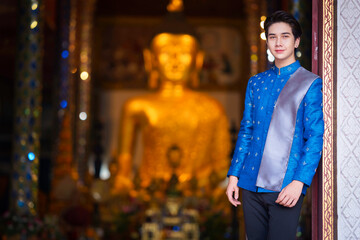 Obraz premium Handsome man wearing a beautiful Thai national costume in Lantern Festival or Yi Peng Festival for worship at Phra That Hariphunchai temple in Lamphun, Northern Thailand.