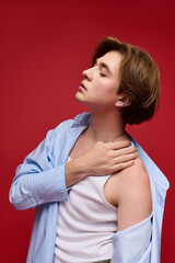 Obraz premium Stylish young man showcases trendy outfit against vibrant red backdrop in fashion shoot