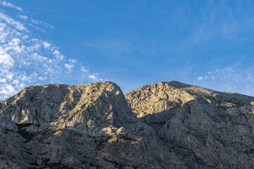 Fototapeta premium Gray rocks with small vegetation against the sky. Mountain landscape, Croatia. copy space
