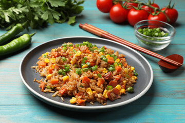 Delicious fried rice with vegetables and bacon served on light blue wooden table, closeup