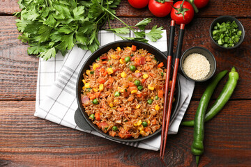 Delicious fried rice in baking dish served on wooden table, flat lay
