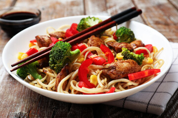 Delicious noodles with meat and vegetables served on wooden table, closeup
