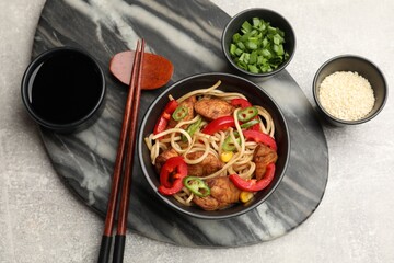 Tasty noodles with chicken and vegetables served on light grey table, flat lay