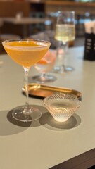 Cocktail glass with amber drink on a table with mixed beverages in soft focus background