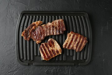 Delicious grilled beef meat on black textured table, top view