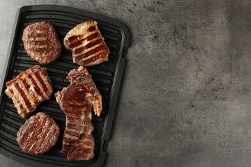 Delicious grilled beef meat on grey table, top view. Space for text