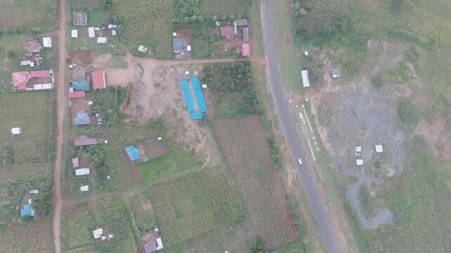 Aerial view of roads intersecting through lush green fields dotted with buildings and trees, creating a textured landscape, Nakuru, Nakuru County, Kenya.