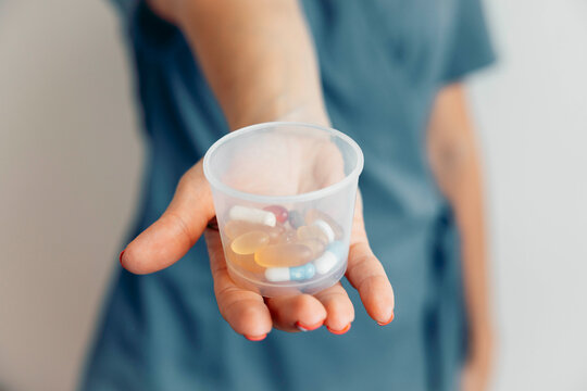 Nurse holding plastic container with assorted pills and capsules