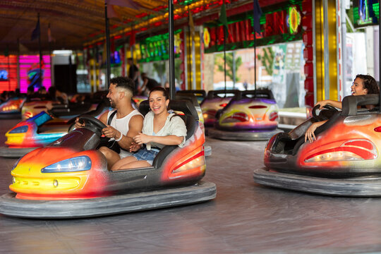 Friends enjoying bumper car ride together at a colorful fair