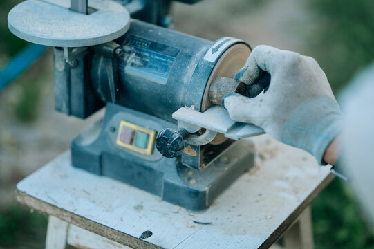 Hand sanding wood using electric sander in outdoor workshop
