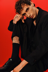 Stylish man showcasing elegance in a bold fashion statement against a vibrant red backdrop