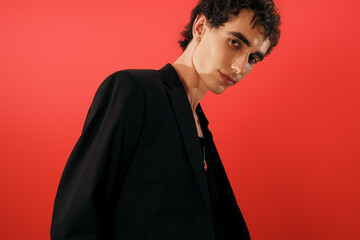 Obraz premium Handsome stylish man embodies elegance in striking outfit against vibrant red backdrop
