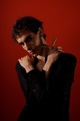 Obraz premium Stylish man poses elegantly against a vivid red backdrop showcasing his fashion sense