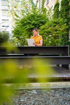 Businesswoman using tablet PC on table near plants