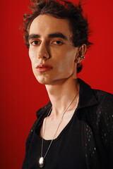 Stylish man exudes elegance with a confident look against a vibrant red backdrop