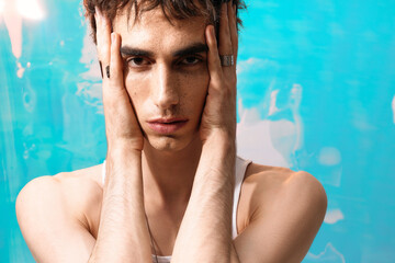 Stylish man exudes elegance with striking expression against a vibrant blue backdrop