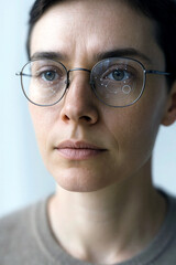 Close-up of a serious caucasian woman wearing smart glasses with a futuristic heads-up display on the lenses. Augmented reality and artificial intelligence concept