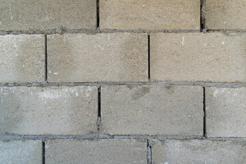 Fototapeta premium Gray concrete block wall features visible texture and imperfections, highlighting construction materials, suitable for backgrounds or architectural design projects with copy space for text