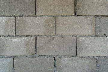 Gray concrete block wall features visible texture and imperfections, highlighting construction materials, suitable for backgrounds or architectural design projects with copy space for text