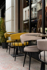 Outdoor cafe area with modern minimalist furniture, featuring yellow and beige chairs around a marble table, ideal for cafes, restaurants, outdoor furniture, leisure, tourism and lifestyle themes