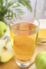 Fresh cider in glass, bottle and apples on table, closeup
