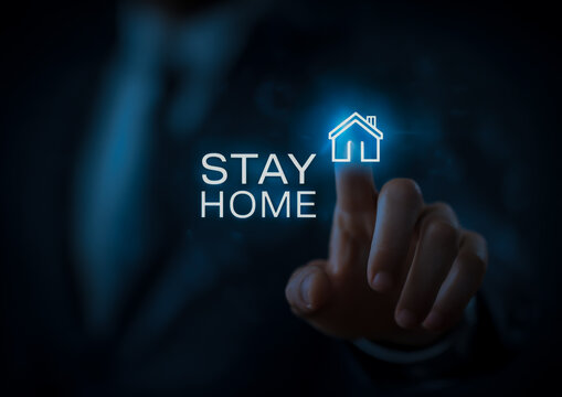 Finger pressing glowing blue neon text stay home with house icon on dark background