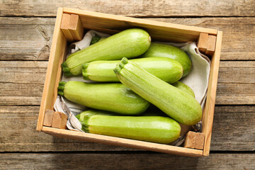 Fresh ripe zucchinis in crate on wooden table, top view