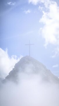 Summit cross atop a peak, shrouded in mist