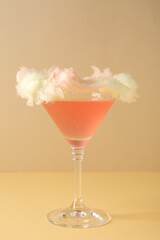 Tasty cocktail decorated with cotton candy on color background, closeup