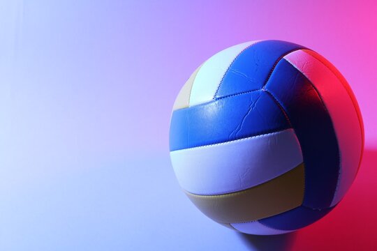 Colorful volleyball ball on light background in color lights. Space for text