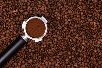 Holder with ground coffee on the background of roasted coffee beans. Coffee horn and coffee beans background texture.