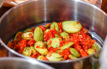 Traditional Southeast Asian food: spicy stink beans (petai) mixed with chili sambal served in a stainless steel bowl.